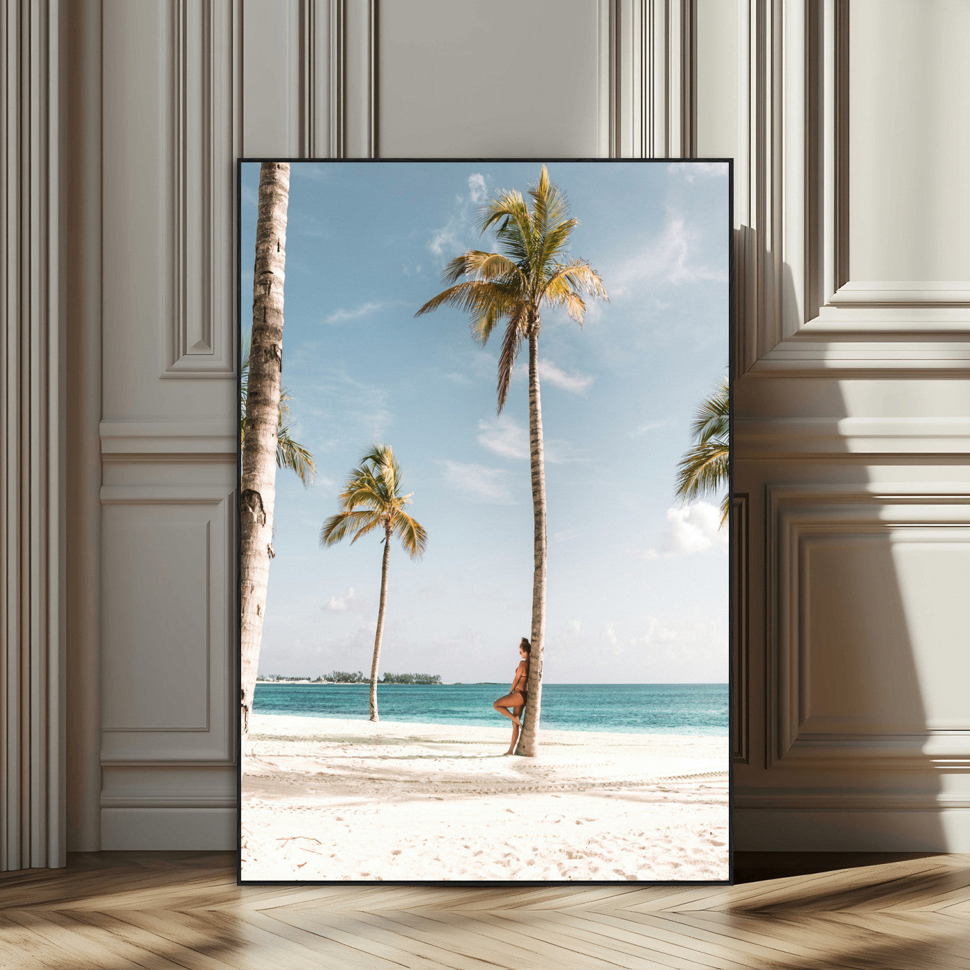 Person leaning on a palm tree at a tropical beach with white sand and turquoise water, perfect for coastal or beach-themed home decor.