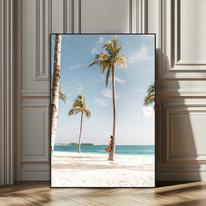 Person leaning on a palm tree at a tropical beach with white sand and turquoise water, perfect for coastal or beach-themed home decor.