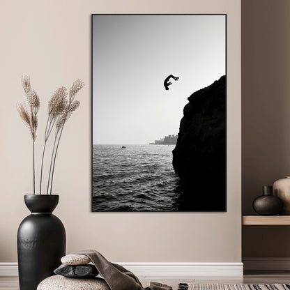 Silhouette of a person mid-air during a cliff jump over the ocean, captured in black and white for minimalist adventure decor.