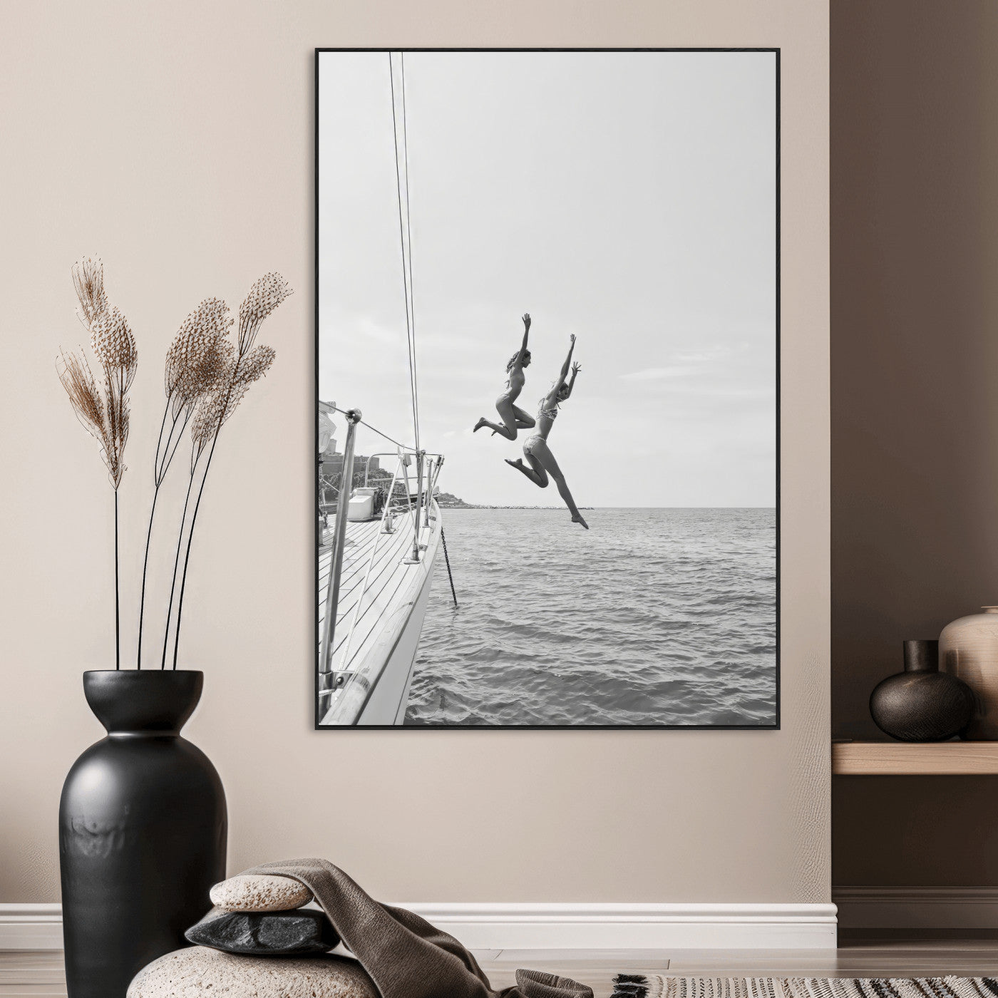 Black and white canvas wall art of two women joyfully jumping off a yacht into the sea, ideal for minimalist coastal or nautical-themed spaces.