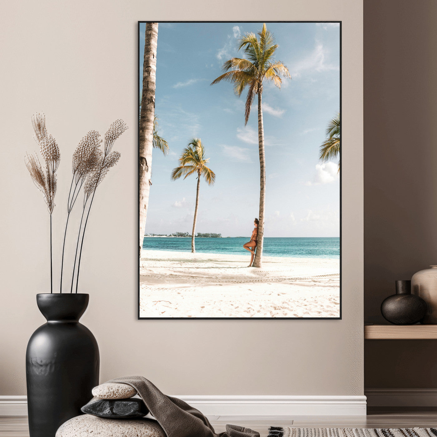 Person leaning on a palm tree at a tropical beach with white sand and turquoise water, perfect for coastal or beach-themed home decor.