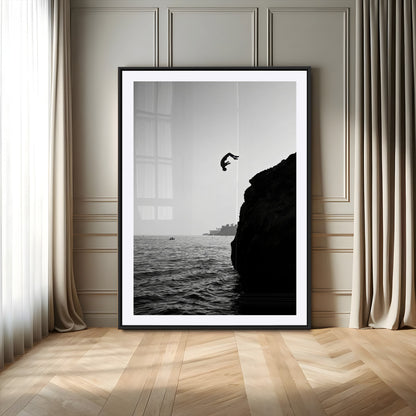 Silhouette of a person mid-air during a cliff jump over the ocean, captured in black and white for minimalist adventure decor.