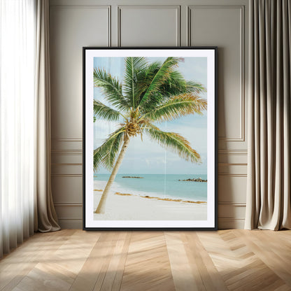 A tall palm tree leaning over a white sandy beach with turquoise ocean waves, creating a peaceful and tropical coastal scene.