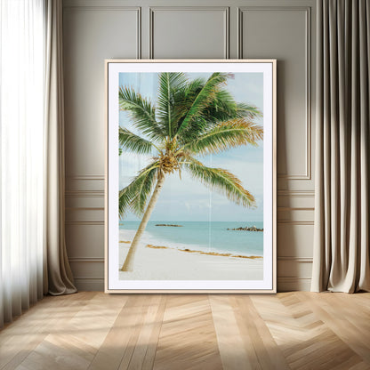 A tall palm tree leaning over a white sandy beach with turquoise ocean waves, creating a peaceful and tropical coastal scene.