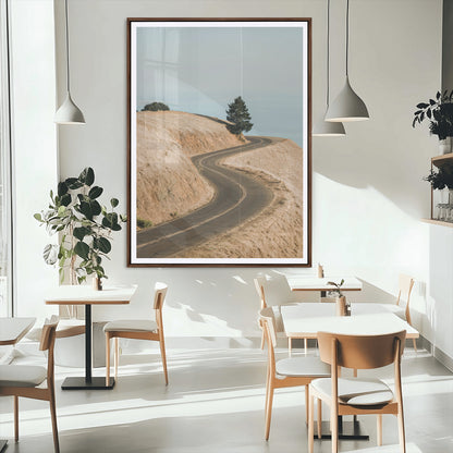 Earth-toned photograph of a winding road through golden hills, ideal for neutral or rustic-themed decor with a calming travel vibe.