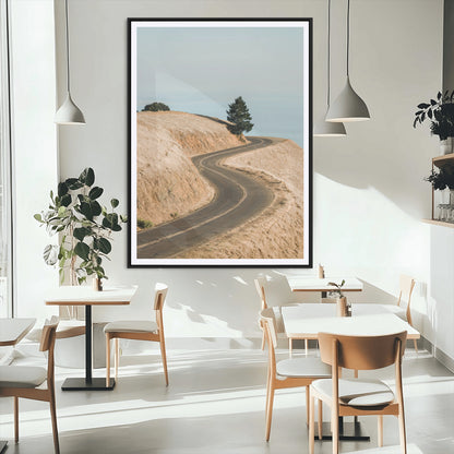 Earth-toned photograph of a winding road through golden hills, ideal for neutral or rustic-themed decor with a calming travel vibe.