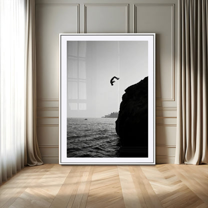 Silhouette of a person mid-air during a cliff jump over the ocean, captured in black and white for minimalist adventure decor.