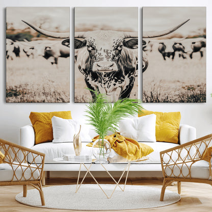 Canvas of a speckled Texas longhorn standing boldly in a field with a herd behind, perfect for rustic western or farmhouse wall decor.