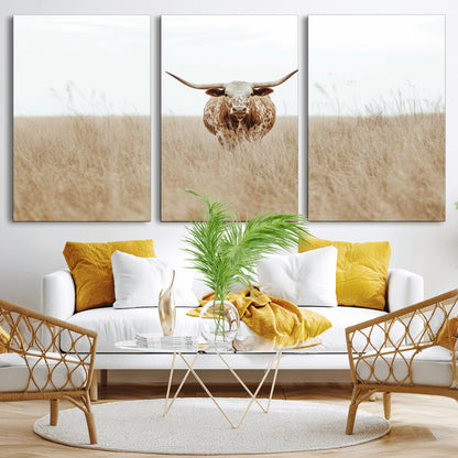 Texas Longhorn bull standing alone in dry grass with neutral tones, ideal for rustic western or cowboy-themed wall decor.