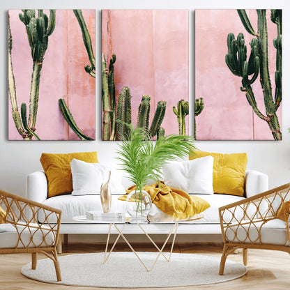 Framed canvas of tall green cacti against a soft pink wall, ideal for modern desert or colorful southwest-inspired home decor.