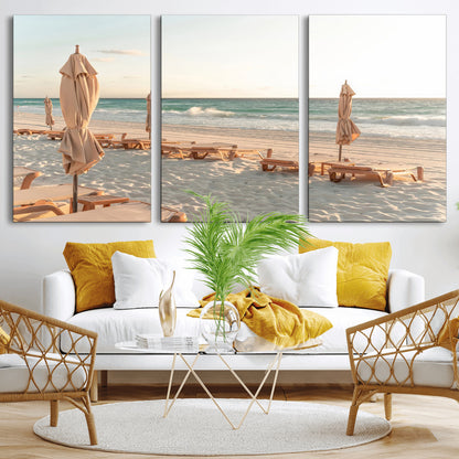 Minimalist photo of empty beach loungers and umbrellas on soft sand, ideal for calm seaside or pastel coastal-style home decor.