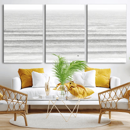 Monochrome photo of a lone surfer in calm layered waves, perfect for minimalist coastal or moody ocean-inspired wall decoration.