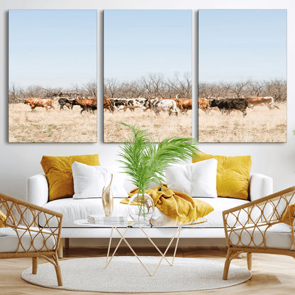 Framed wall art of Texas longhorn cattle walking through a dry, neutral-toned prairie, perfect for rustic farmhouse or western-themed home decor.