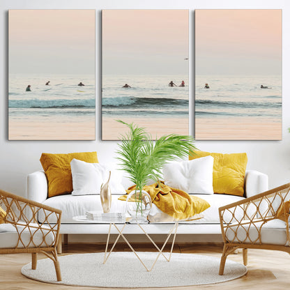 Dreamy photo of surfers waiting on soft pastel waves under a pink sunset sky, ideal for soft coastal minimalist or serene ocean-themed home decor.