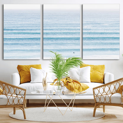 Minimalist ocean view with soft blue waves and a lone surfer, creating a serene and airy coastal aesthetic, perfect for tranquil home decor.