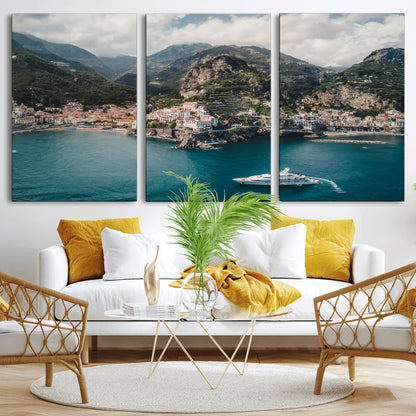 Aerial view of Amalfi Coast, Italy, with colorful hillside houses, lush green mountains, and a luxury yacht sailing in turquoise waters.