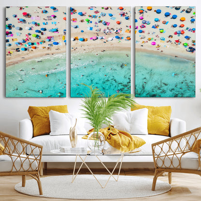 Aerial view of a vibrant beach filled with colorful umbrellas and people enjoying the turquoise ocean, capturing a lively summer vacation scene.