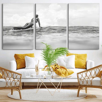 A black and white ocean scene featuring a surfer girl waiting on her board, gazing at the horizon, capturing a tranquil and adventurous coastal moment.