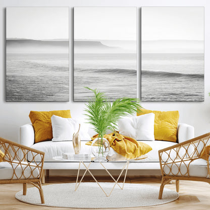 A black and white minimalist seascape featuring soft rolling waves and misty distant cliffs, creating a serene and timeless coastal atmosphere.