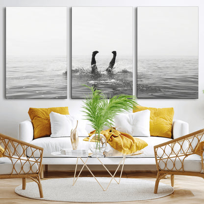 A black and white minimalist water scene capturing a playful splash as a swimmer dives upside down, creating a carefree and artistic aquatic aesthetic.