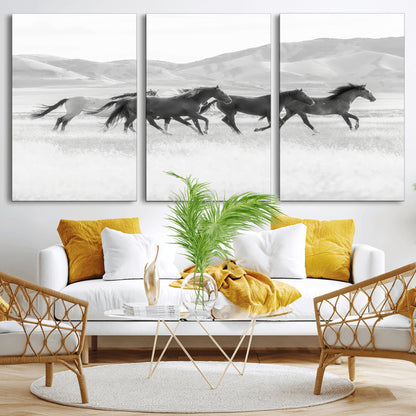 A black and white image of wild horses running freely across an open grassland, capturing the power and beauty of untamed nature in a rustic western setting.