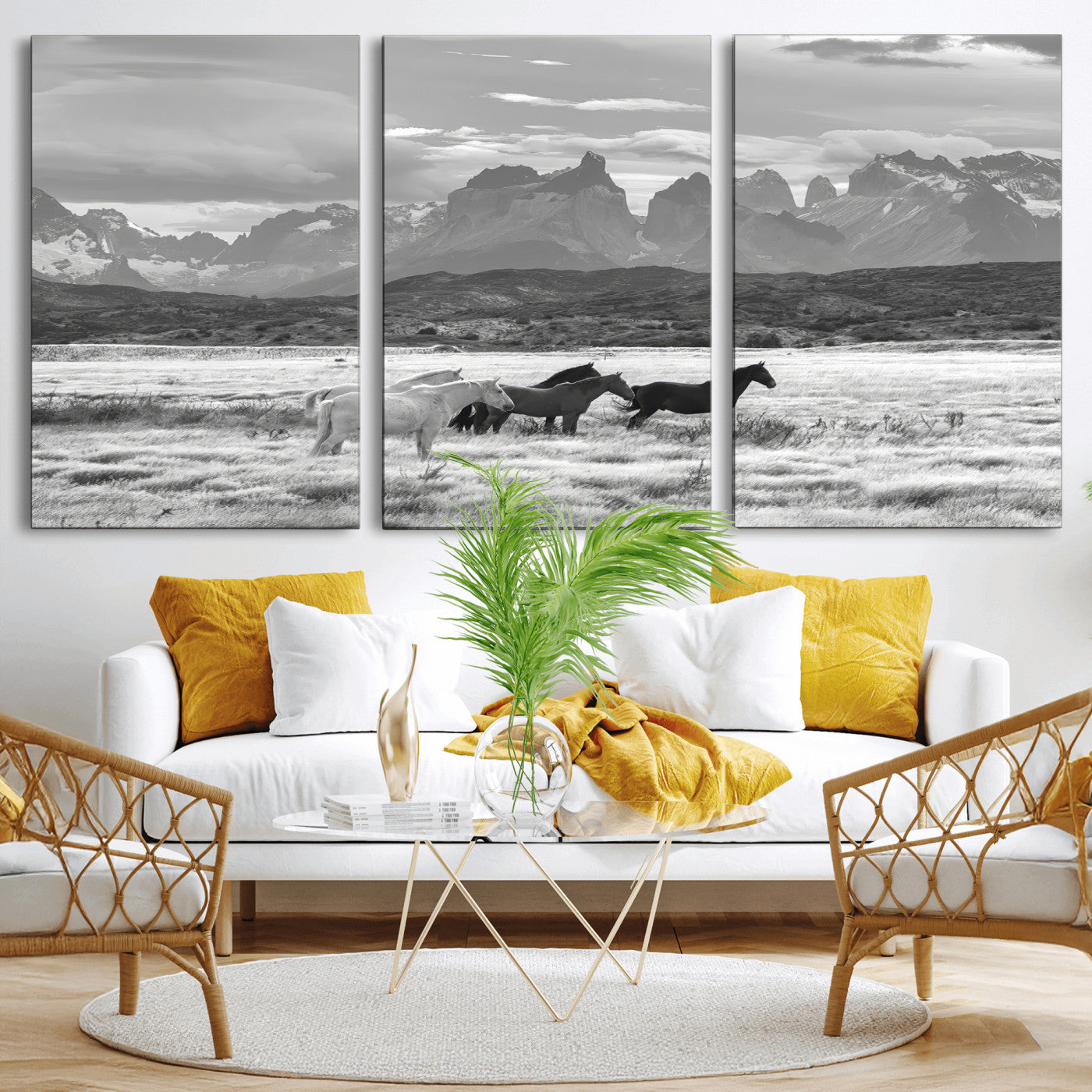 A black and white landscape of wild horses grazing in a vast grassland with towering mountains in the background, creating a moody and rustic western aesthetic.