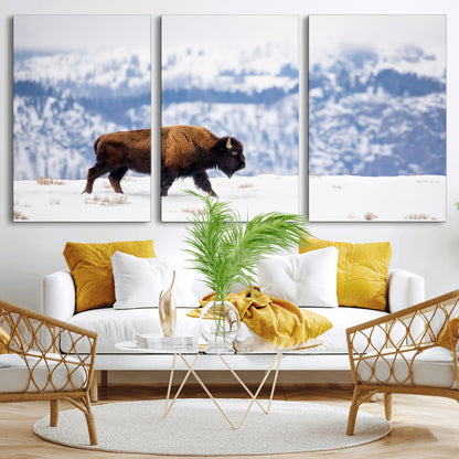A lone bison walks across snowy ground with blue-toned mountain range behind, ideal for rustic or western farmhouse interiors.