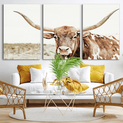 A Texas longhorn bull with wide horns, standing in a dry field under soft light, ideal for rustic farmhouse or western-themed interiors.