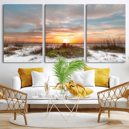 A tranquil beach scene featuring golden sunset hues over the water, with grasses in the foreground and a peaceful, serene atmosphere.