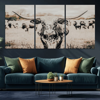 Canvas of a speckled Texas longhorn standing boldly in a field with a herd behind, perfect for rustic western or farmhouse wall decor.