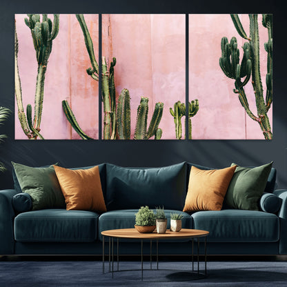 Framed canvas of tall green cacti against a soft pink wall, ideal for modern desert or colorful southwest-inspired home decor.