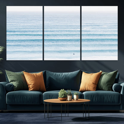 Minimalist ocean view with soft blue waves and a lone surfer, creating a serene and airy coastal aesthetic, perfect for tranquil home decor.