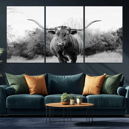 Black and white photo of a longhorn cow in a field, perfect for rustic farmhouse or western-themed interior wall decoration.
