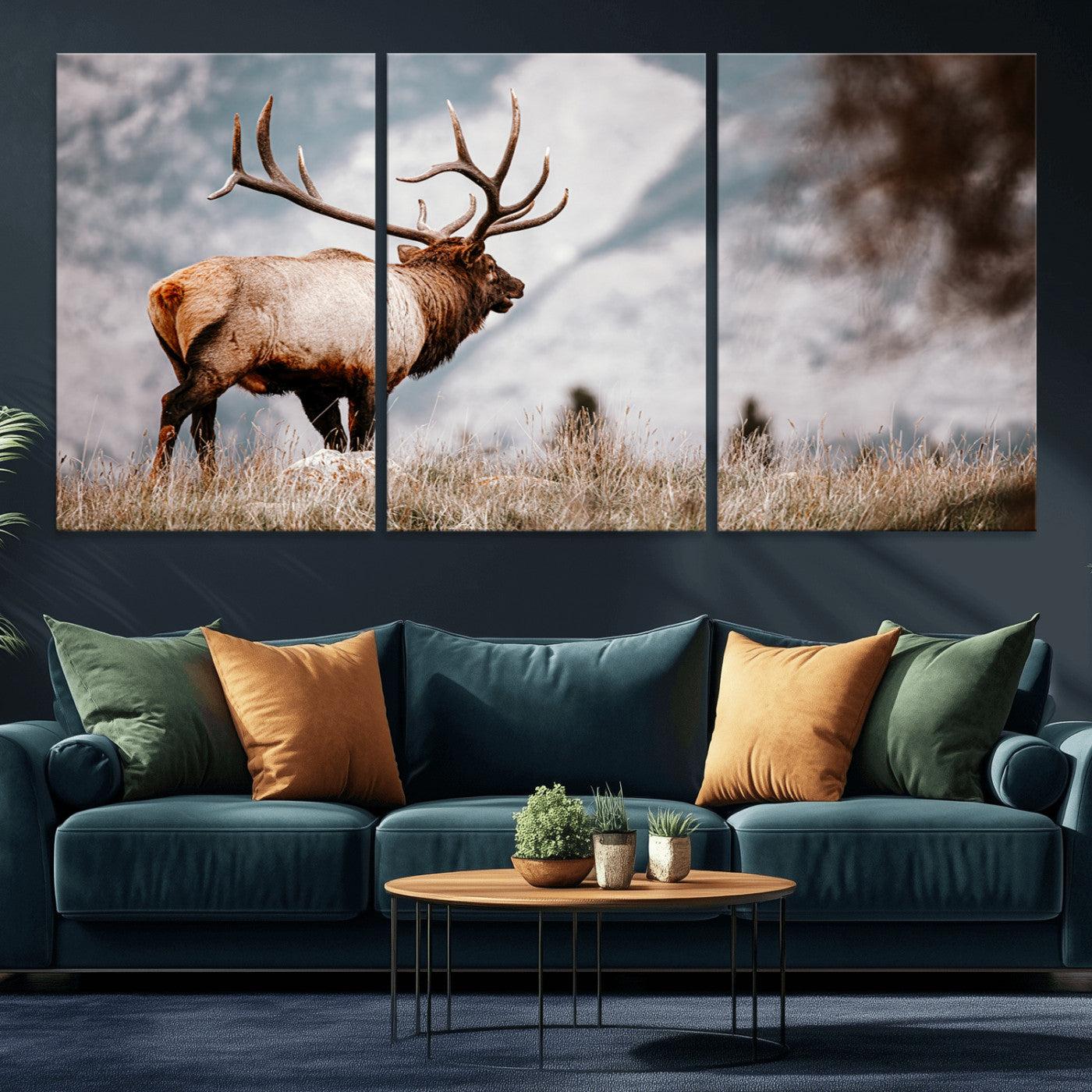 Majestic elk with large antlers standing in grass with snowy mountains in background, perfect for rustic cabin or lodge style decor.