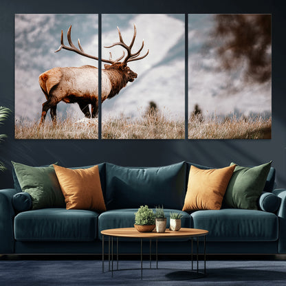 Majestic elk with large antlers standing in grass with snowy mountains in background, perfect for rustic cabin or lodge style decor.