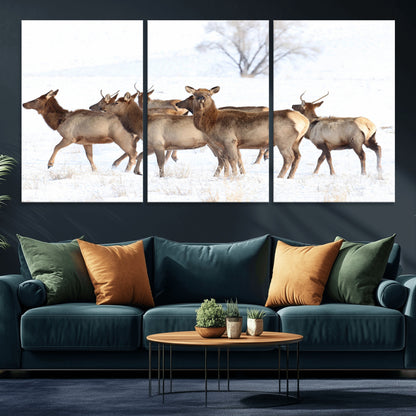 A group of elk standing on snowy terrain with a tree in the background, perfect for rustic or lodge-style winter wall decor.