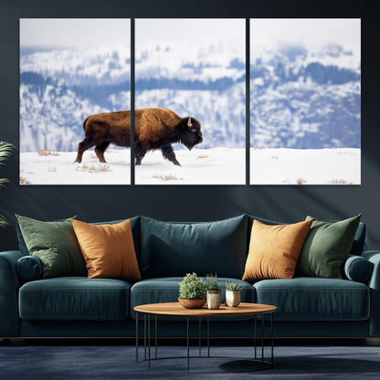 A lone bison walks across snowy ground with blue-toned mountain range behind, ideal for rustic or western farmhouse interiors.