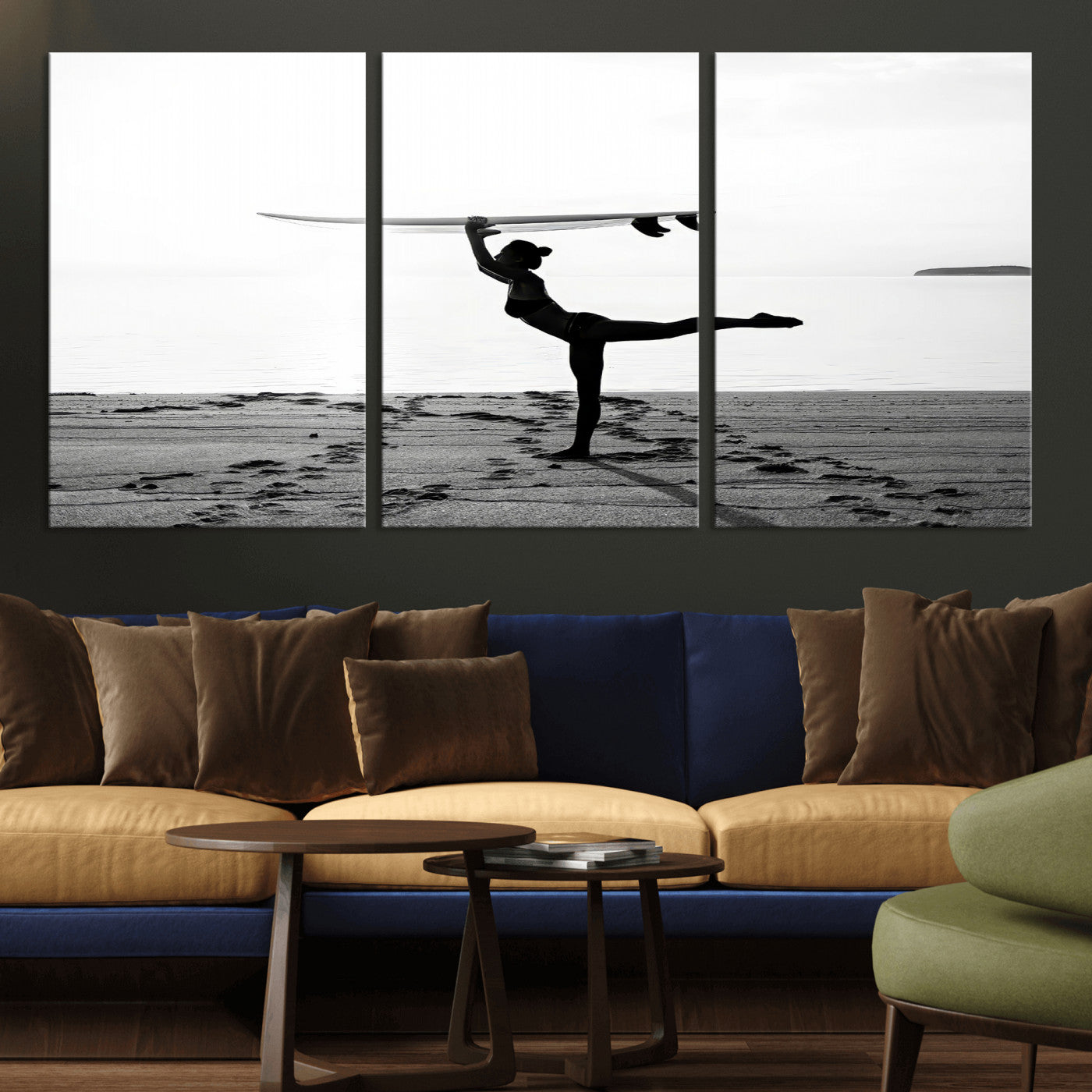 A woman balances a surfboard on her head while striking a yoga pose on the beach, silhouetted against a calm ocean horizon.