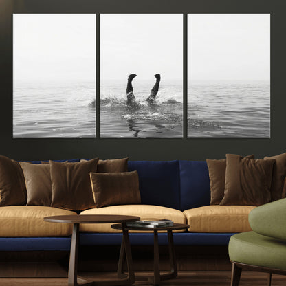 A black and white minimalist water scene capturing a playful splash as a swimmer dives upside down, creating a carefree and artistic aquatic aesthetic.
