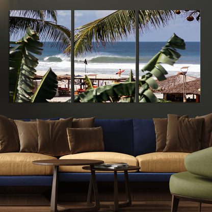 Canvas wall art of a tropical surf scene framed by palm trees, with a surfer on the shore and waves rolling in, ideal for beach-themed decor.