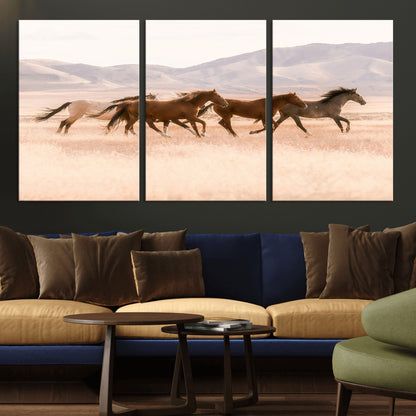 A herd of wild horses galloping through a sunlit desert plain with mountains in the background, perfect for rustic or western-themed wall decor.