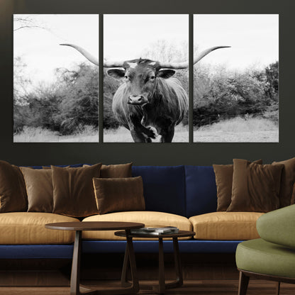 Black and white photo of a longhorn cow in a field, perfect for rustic farmhouse or western-themed interior wall decoration.