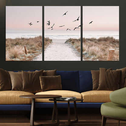 A peaceful coastal pathway leading to the ocean, with birds flying across a soft pastel sky, creating a calm and scenic beach atmosphere.