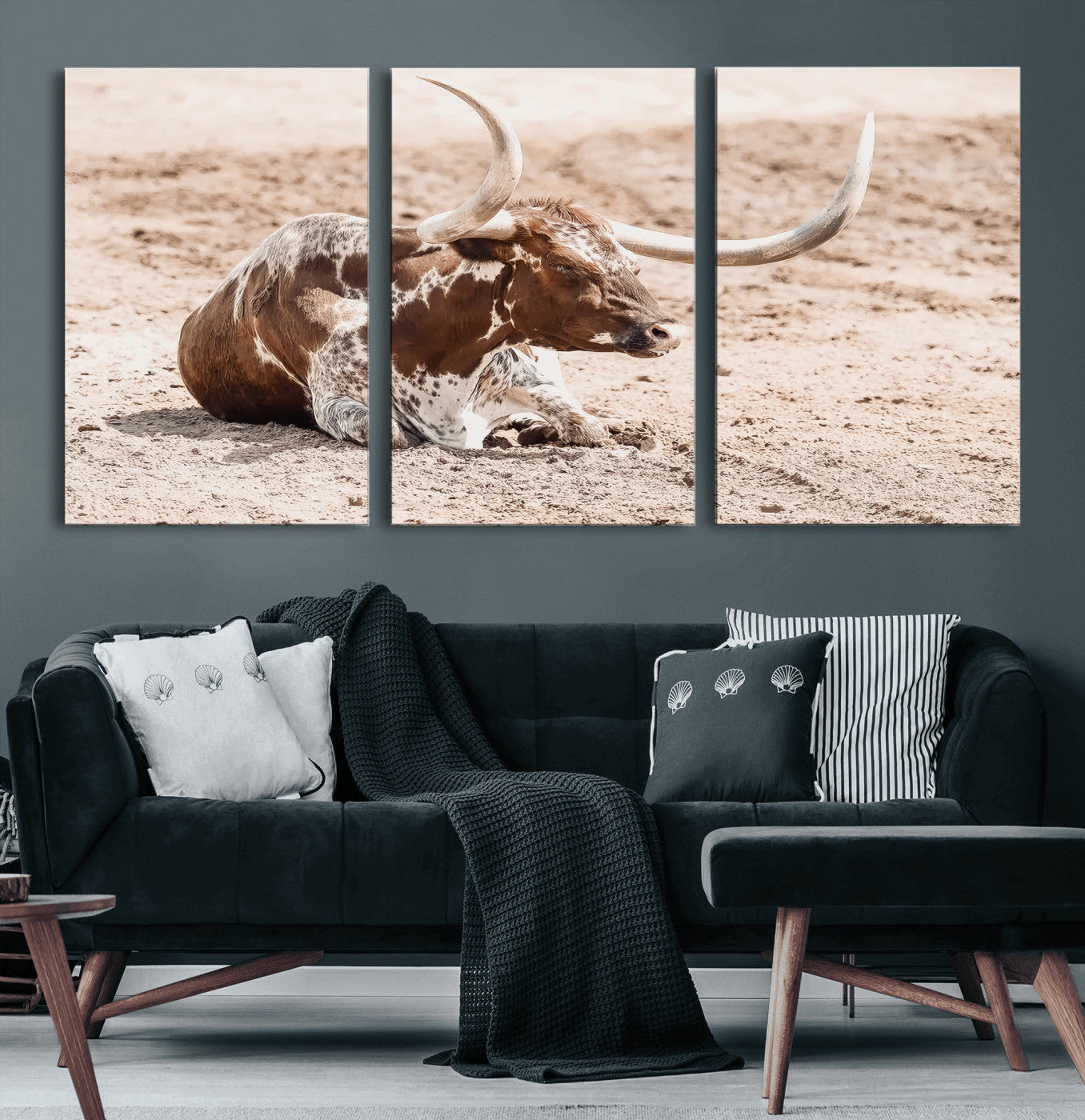 Texas Longhorn bull resting on dusty ground with warm tones, ideal for rustic western or farmhouse-themed wall decor.