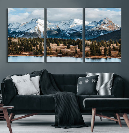 Framed canvas of snowy mountain peaks with pine forest and alpine lake, perfect for winter cabin or wilderness-inspired home decor.