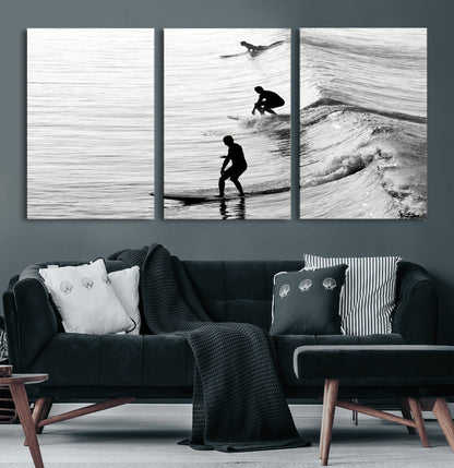 Black and white photo of surfers riding waves in a moody, high-contrast scene, ideal for modern coastal or surf-inspired home decor.