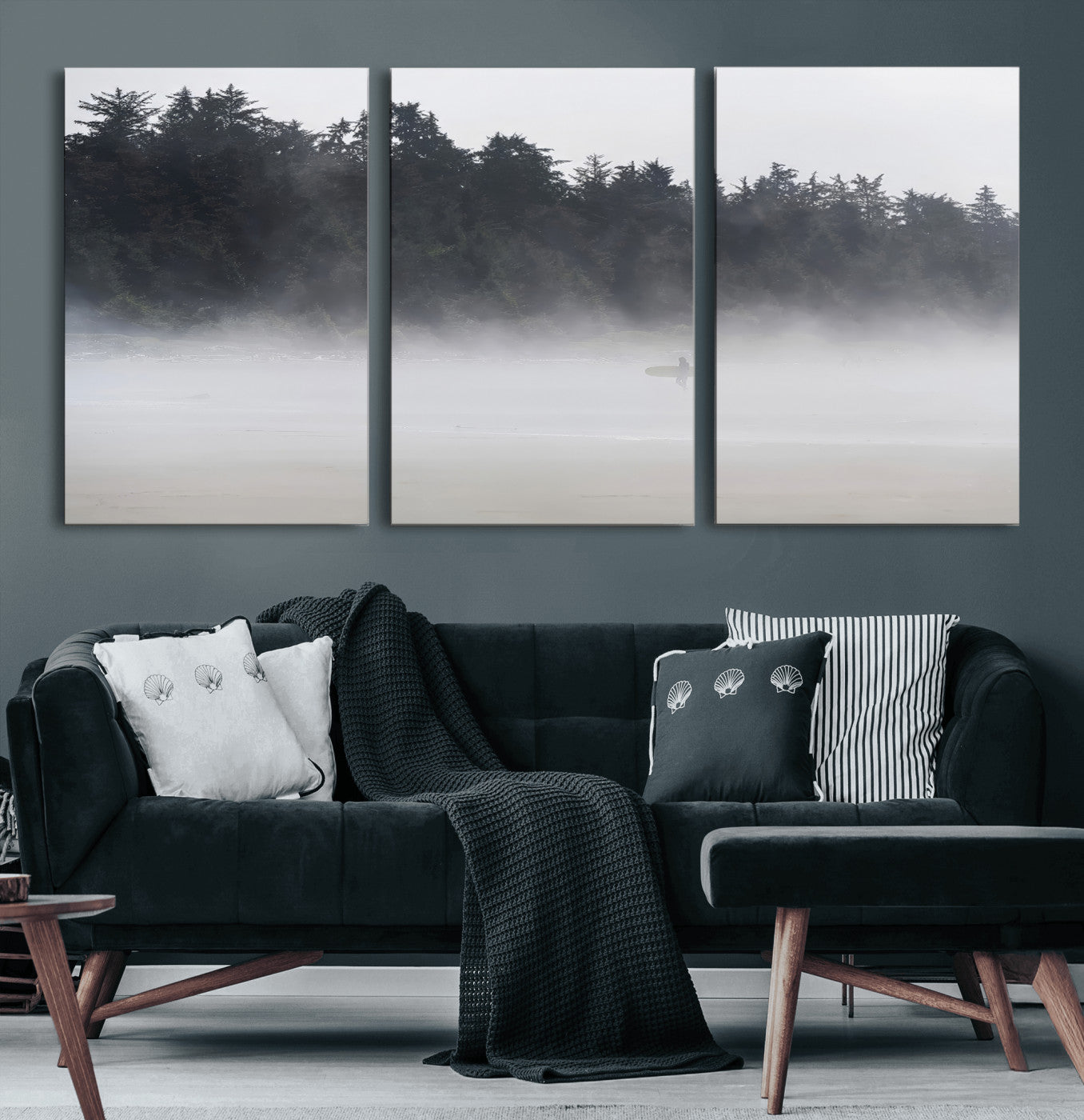 A lone surfer carrying a board through a misty shoreline, surrounded by dense trees and fog, creating a peaceful and mysterious coastal scene.