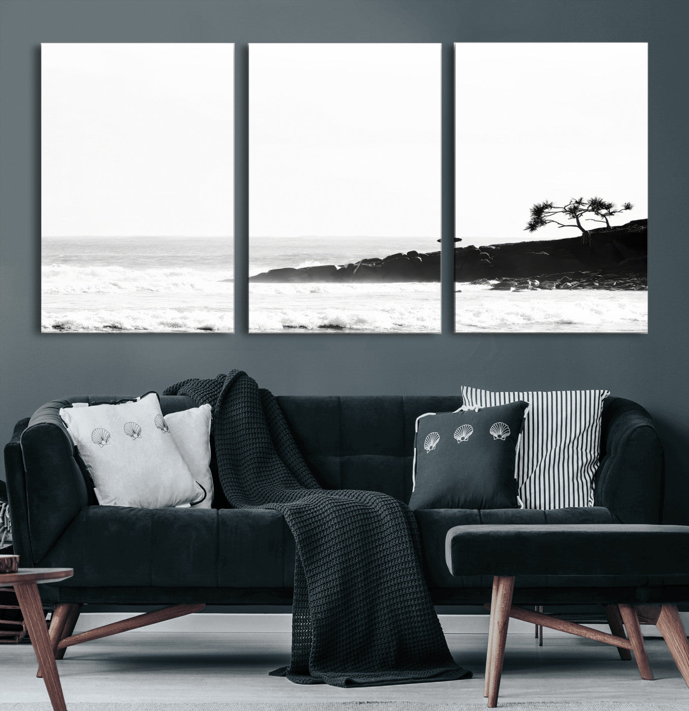 Black and white photo of a surfer standing on rocky cliffs, gazing at the waves, embodying the spirit of adventure and solitude.