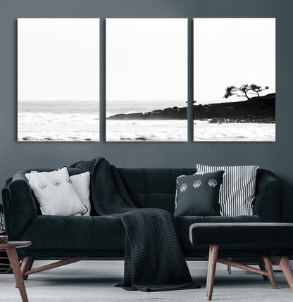 Black and white photo of a surfer standing on rocky cliffs, gazing at the waves, embodying the spirit of adventure and solitude.