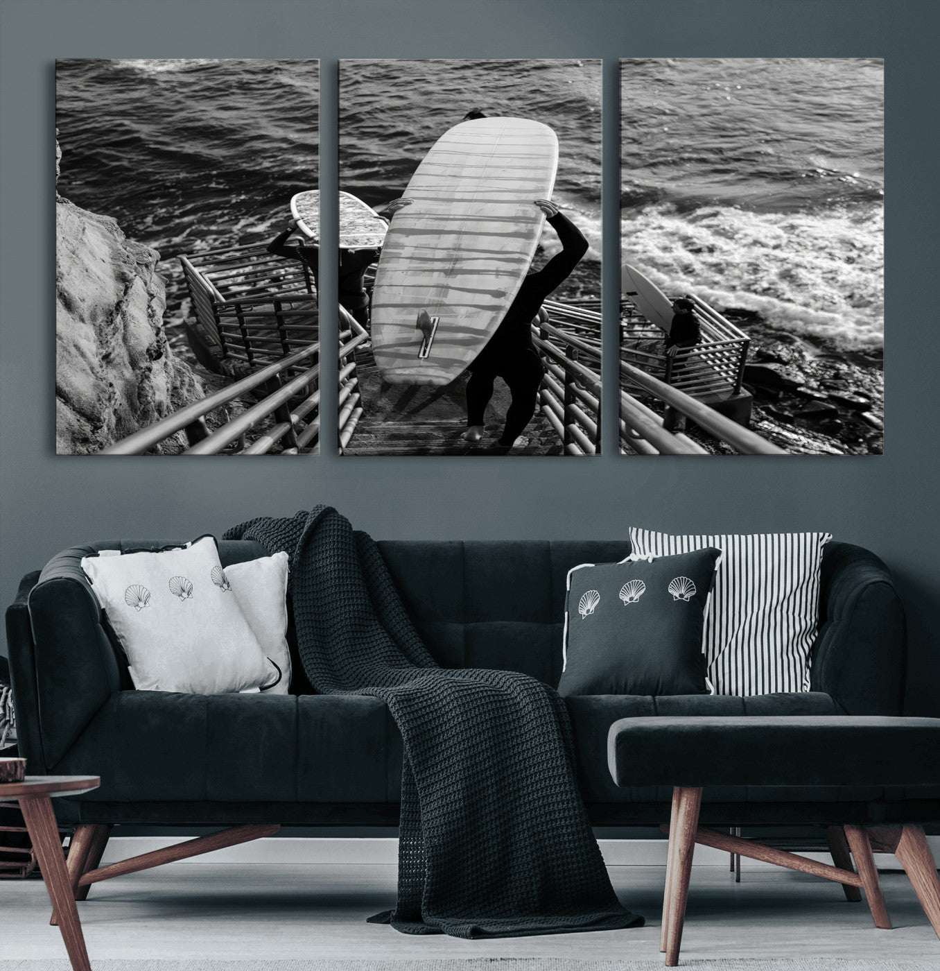Black and white photo of surfers carrying boards down a rugged cliffside stairway, capturing a bold and adventurous coastal scene.